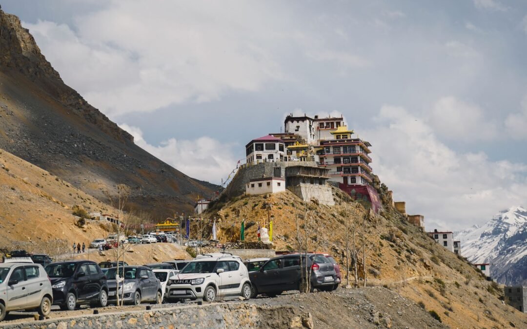 Picturesque view of Key Monastery atop a hill in Spiti Valley, with cars and mountains.