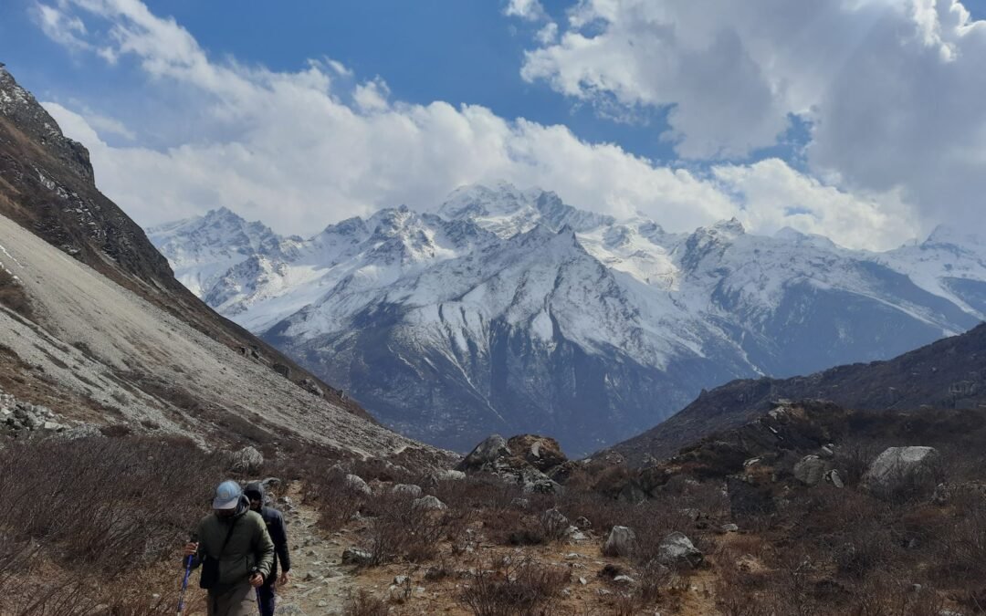 Scenic hike in Nepal's Langtang Valley with snow-capped mountains and cloudy skies.