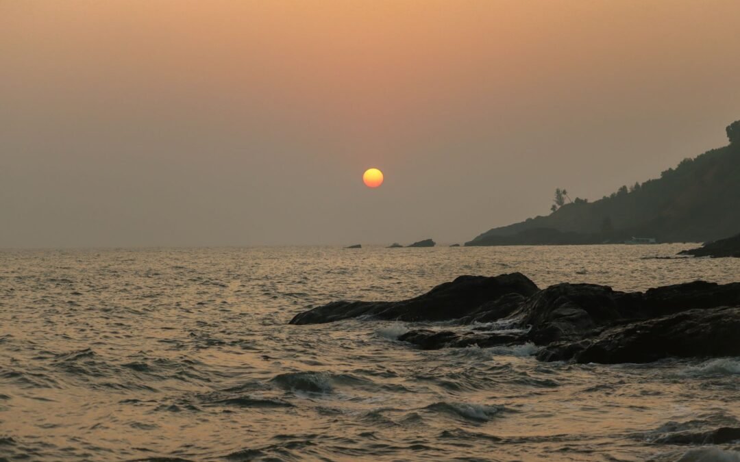 Serene sunset view at Gokarna, India with waves crashing on the rocky shore.