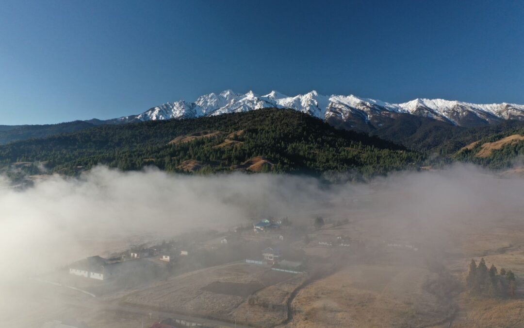 A breathtaking view of a misty valley with snowy mountains in Kargong, perfect for nature and travel enthusiasts.