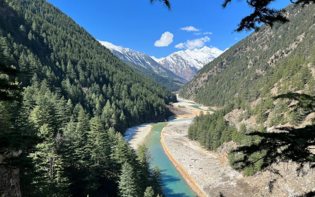 A stunning river meanders through a lush green valley, flanked by towering mountains.